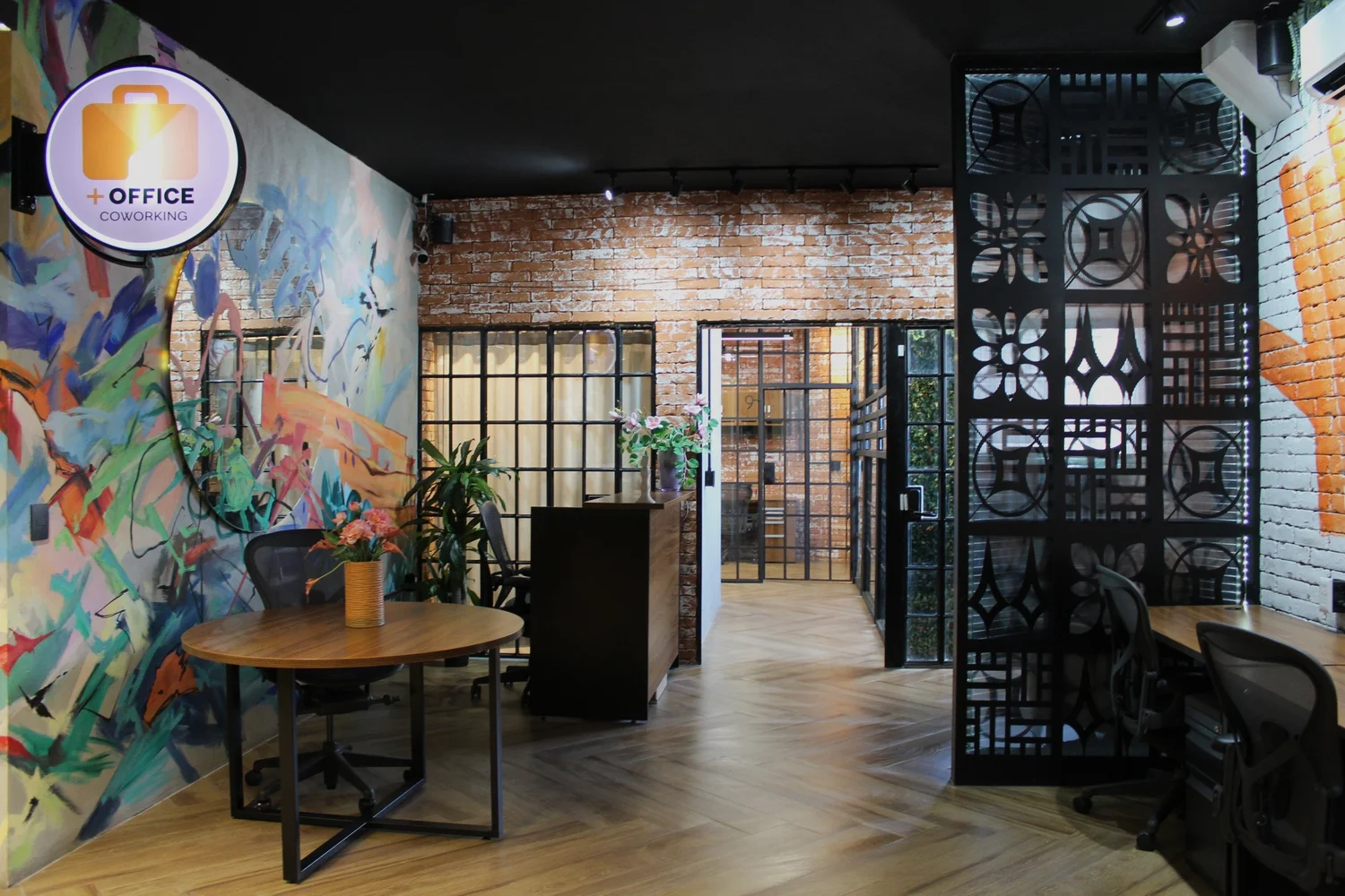 Área de trabajo de Más Office con muros de ladrillo, mural y escritorios
